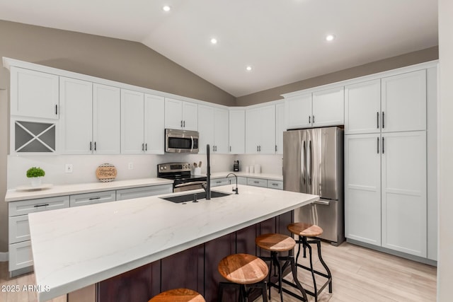 6357 W Potter Dr, Glendale, AZ 85308 - kitchen with appliances with stainless steel finishes, lofted ceiling, a breakfast bar area, an island with sink, and white cabinets