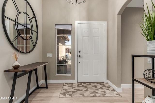 6357 W Potter Dr, Glendale, AZ 85308 - foyer with arched walkways, baseboards, light wood-style floors, and a chandelier