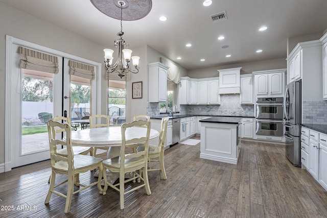 kitchen with pendant lighting, white cabinets, sink, dark hardwood / wood-style floors, and stainless steel appliances