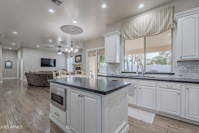 kitchen featuring white cabinets, light hardwood / wood-style flooring, ceiling fan, and sink