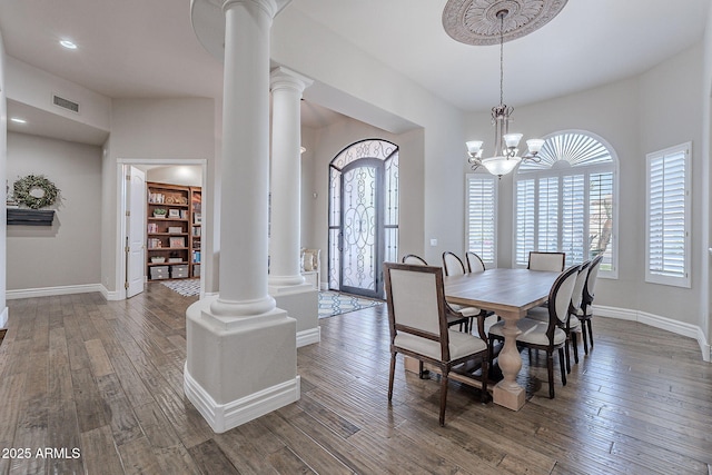 dining space with hardwood / wood-style flooring, ornate columns, and a chandelier