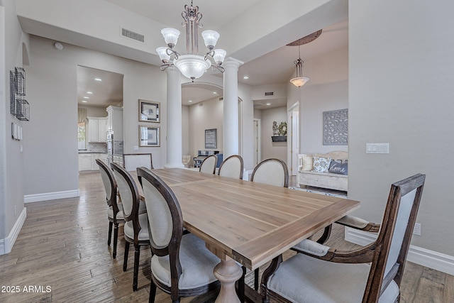 dining space featuring a chandelier, light hardwood / wood-style floors, and decorative columns