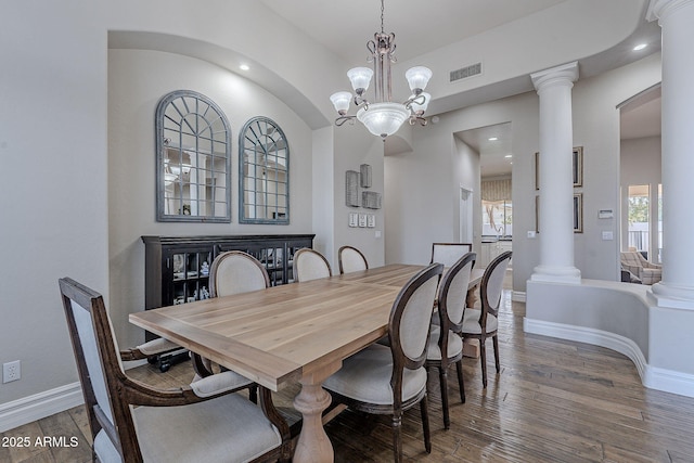 dining area with wood-type flooring, ornate columns, and a notable chandelier