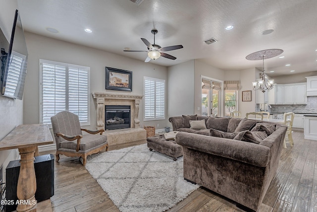 living room with ceiling fan with notable chandelier, light wood-type flooring, and sink