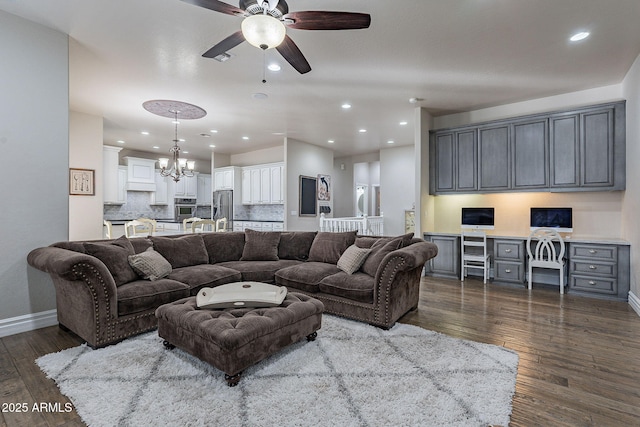 living room featuring dark hardwood / wood-style floors, built in desk, and ceiling fan with notable chandelier