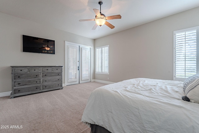 bedroom with ceiling fan, french doors, light carpet, and multiple windows