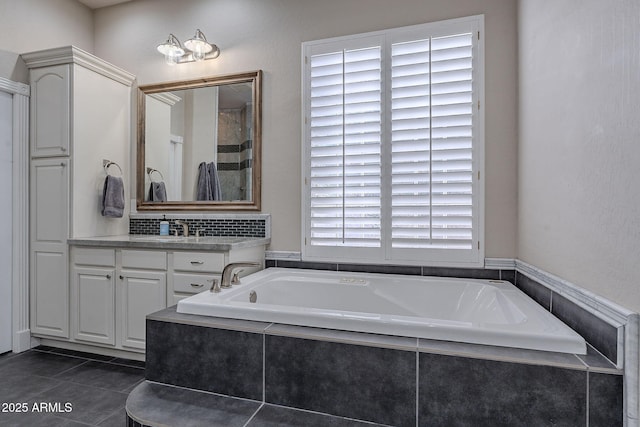 bathroom with tile patterned flooring, vanity, a healthy amount of sunlight, and tiled bath