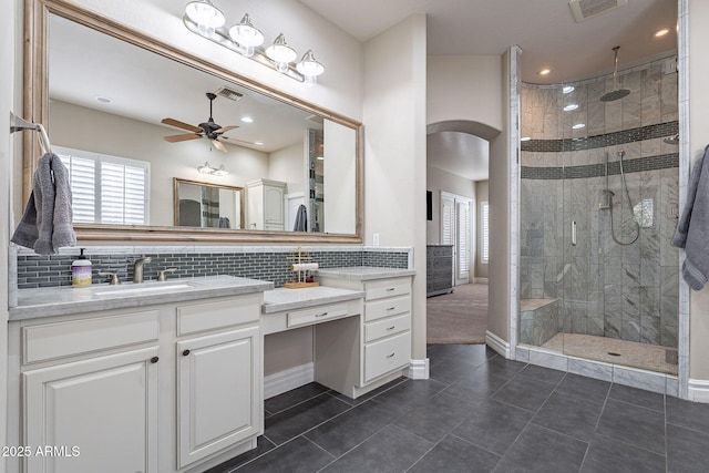 bathroom with ceiling fan, tile patterned flooring, backsplash, tiled shower, and vanity