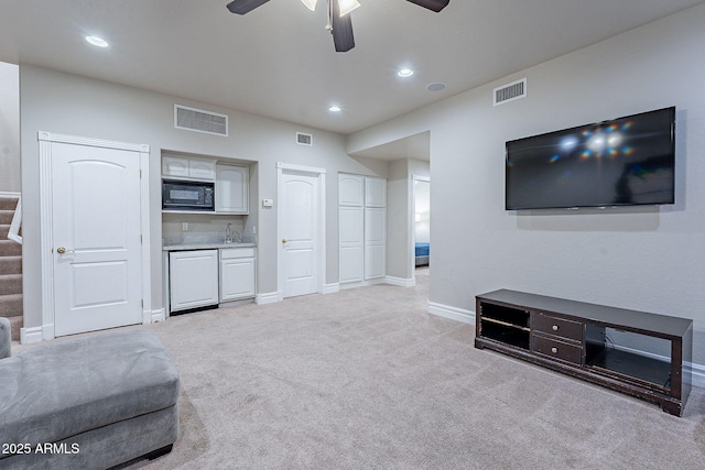 carpeted living room featuring ceiling fan and sink