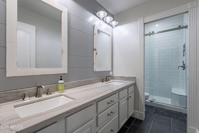 bathroom featuring tile patterned flooring, vanity, toilet, and a shower with door