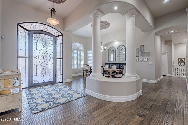 foyer with ornate columns, dark hardwood / wood-style floors, and a notable chandelier