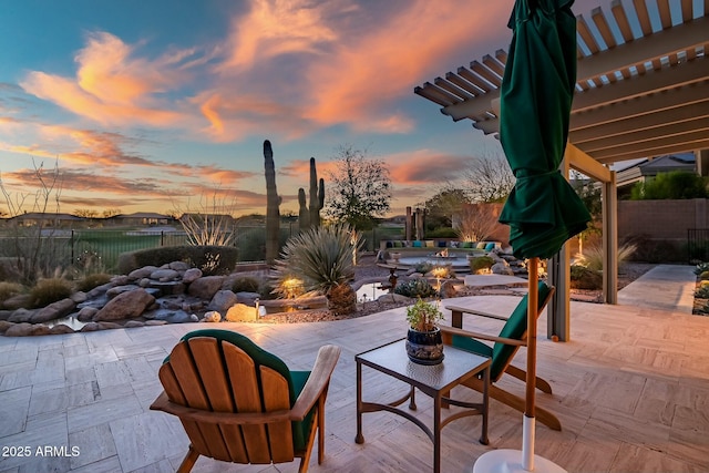 patio terrace at dusk featuring fence and a pergola