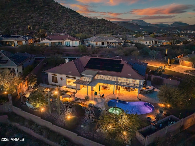 back of property at dusk with a residential view, a patio area, and a mountain view