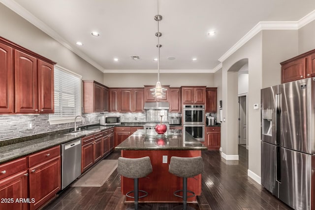 kitchen featuring visible vents, a center island, under cabinet range hood, stainless steel appliances, and a sink