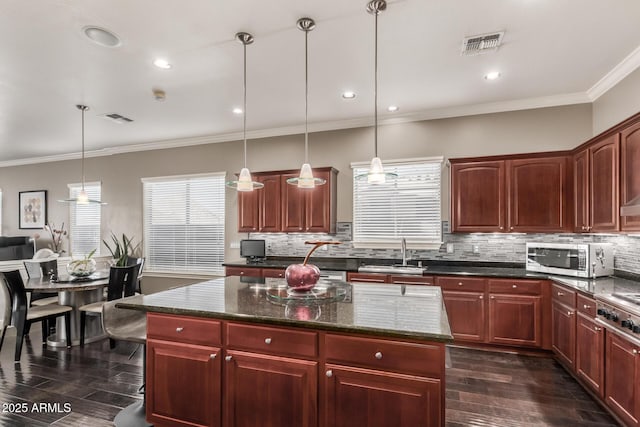 kitchen featuring visible vents, dark wood-type flooring, a sink, stainless steel microwave, and dark brown cabinets