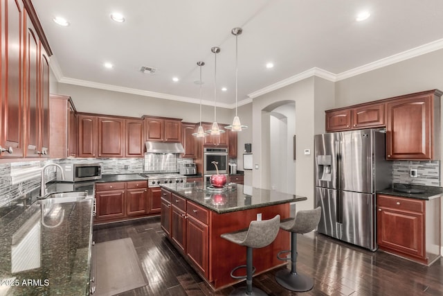 kitchen featuring under cabinet range hood, a sink, a kitchen island, stainless steel appliances, and arched walkways