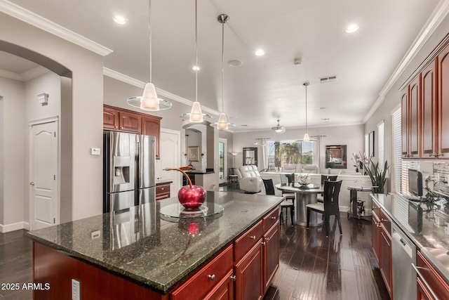 kitchen with stainless steel appliances, arched walkways, reddish brown cabinets, crown molding, and dark wood-style flooring