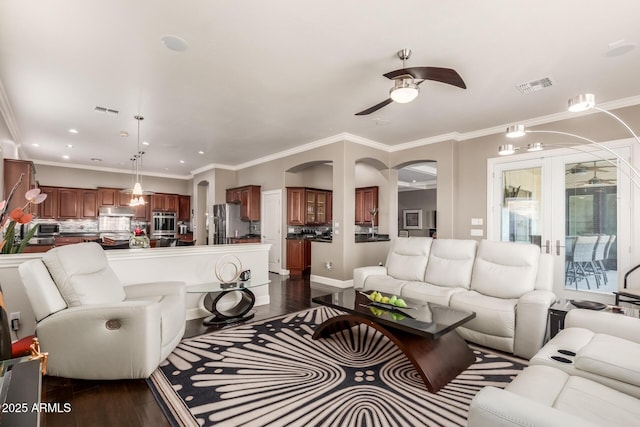 living room featuring visible vents, dark wood-type flooring, ceiling fan, and ornamental molding