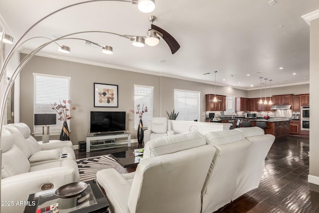 living area with baseboards, a ceiling fan, dark wood-style flooring, and ornamental molding