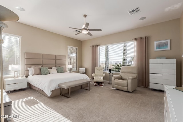 bedroom with light carpet, visible vents, and a ceiling fan