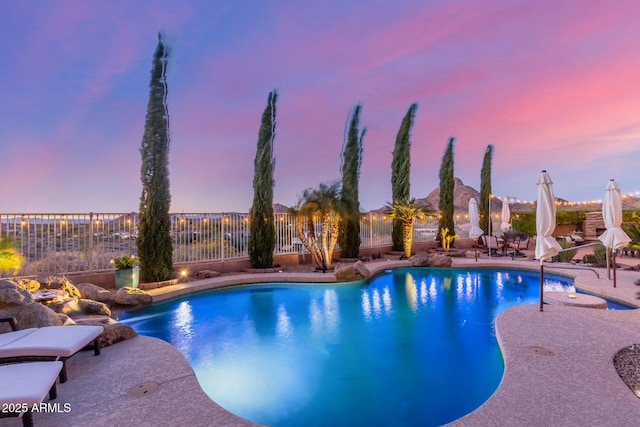 pool at dusk featuring a patio, fence, and a fenced in pool