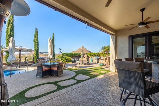 view of patio featuring ceiling fan, a fenced in pool, outdoor dining space, and fence