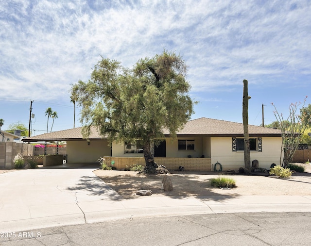 single story home featuring concrete driveway, fence, and an attached carport