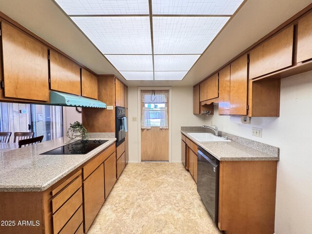 kitchen featuring a sink, light countertops, brown cabinetry, under cabinet range hood, and black appliances