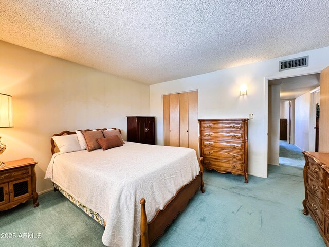 bedroom featuring carpet, a closet, a textured ceiling, and visible vents