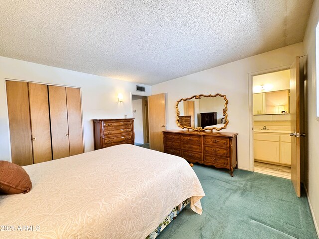 carpeted bedroom featuring a sink, a closet, ensuite bath, and a textured ceiling