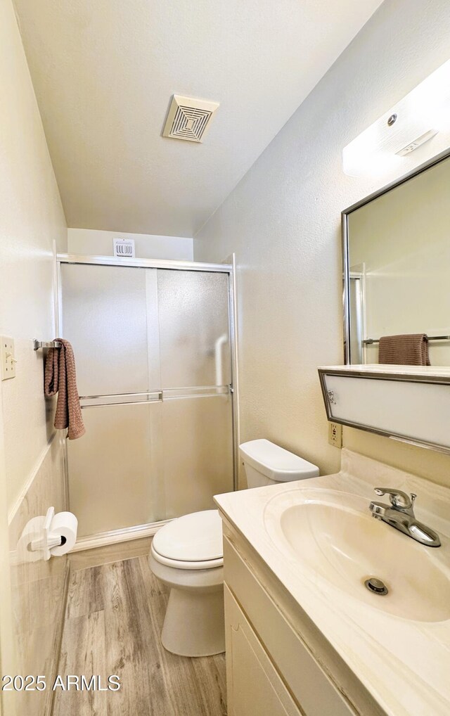 bathroom featuring visible vents, vanity, wood finished floors, toilet, and a stall shower