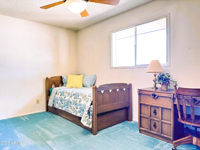 carpeted bedroom featuring a ceiling fan and a textured ceiling