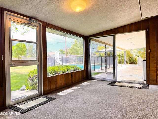 entryway featuring carpet floors, wood walls, and lofted ceiling
