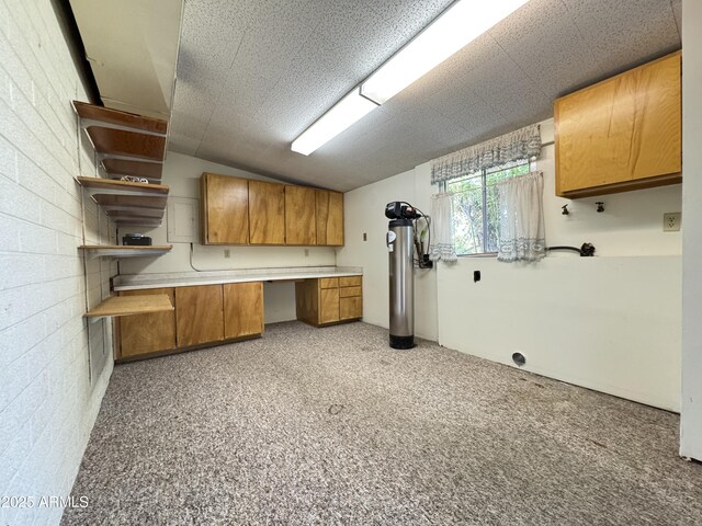 kitchen with brown cabinets, open shelves, built in study area, and light countertops