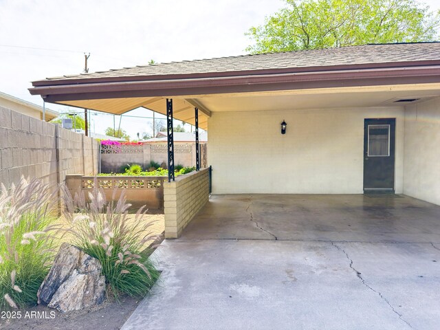 view of vehicle parking featuring fence and a carport