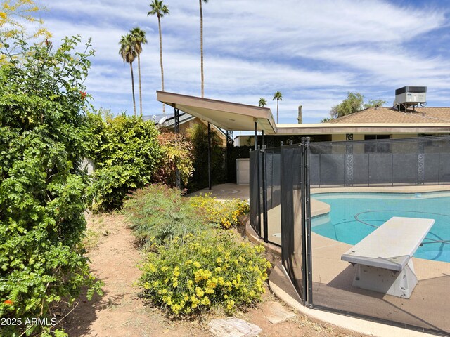 view of swimming pool with a fenced in pool, fence, and a diving board