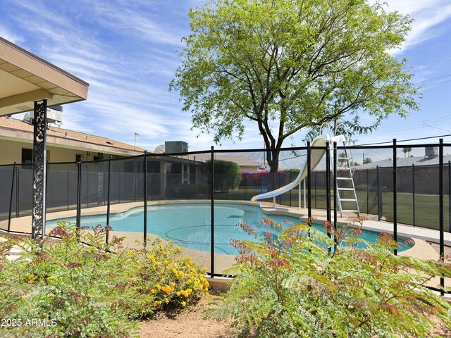 view of swimming pool with fence, a fenced in pool, a water slide, and central AC unit