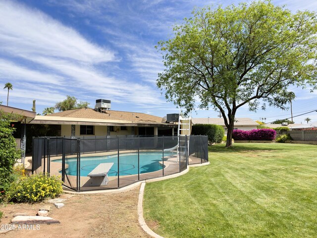 view of swimming pool with a yard, fence, a water slide, and a fenced in pool