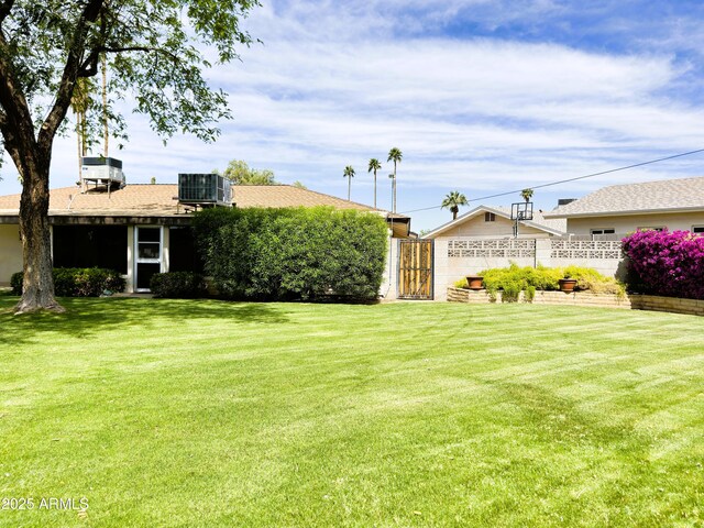 view of yard with a gate, fence, and central AC unit