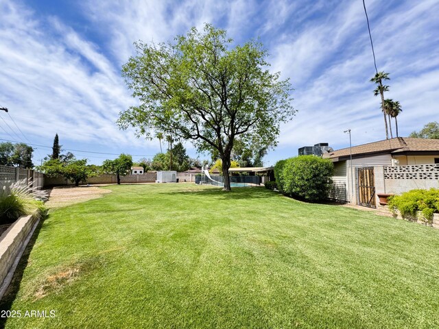 view of yard featuring an outdoor structure, a fenced backyard, and a storage shed