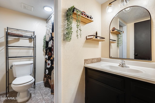 bathroom with tile patterned floors, vanity, a textured ceiling, and toilet