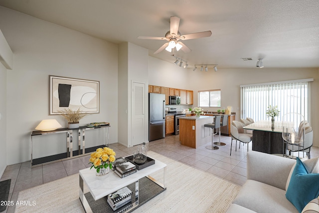 living area with light tile patterned floors, visible vents, a ceiling fan, vaulted ceiling, and track lighting