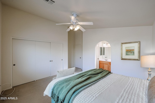 bedroom with arched walkways, lofted ceiling, visible vents, a closet, and carpet