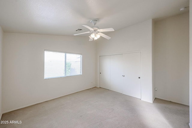 unfurnished bedroom featuring a closet, visible vents, light carpet, ceiling fan, and a textured ceiling