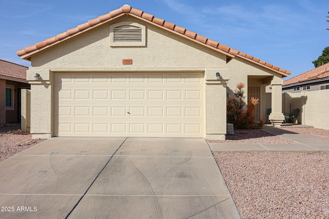 view of front of house featuring an attached garage, driveway, a tiled roof, and stucco siding