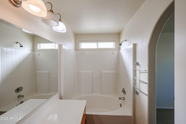 bathroom with a textured wall, shower / bath combination, and vanity