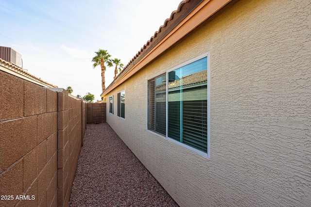 view of side of property featuring a tile roof, a fenced backyard, and stucco siding