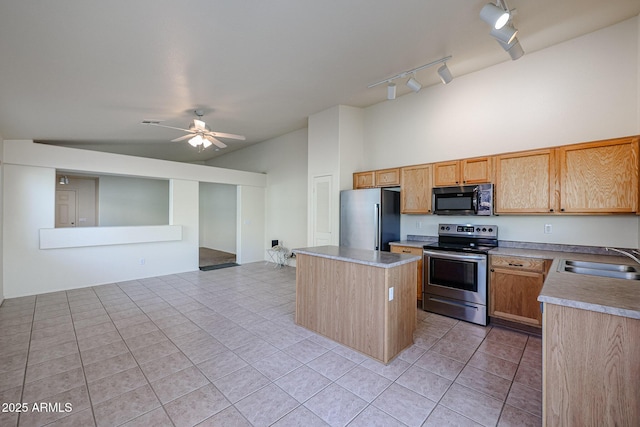 kitchen with a center island, stainless steel appliances, a ceiling fan, light tile patterned flooring, and a sink