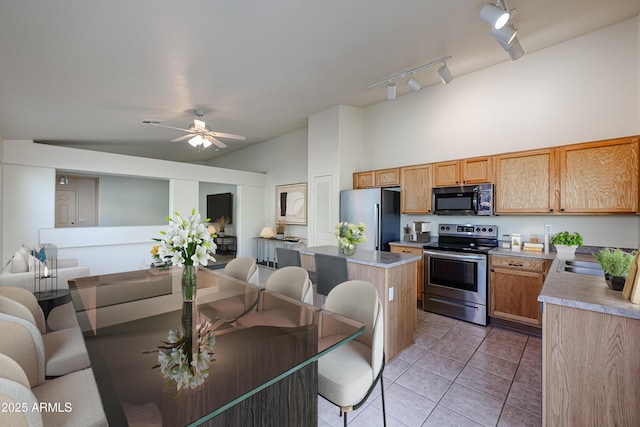 kitchen featuring light tile patterned floors, a kitchen island, appliances with stainless steel finishes, open floor plan, and light countertops