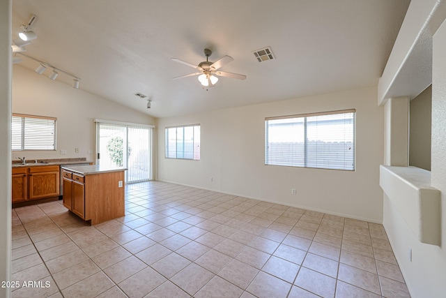 kitchen featuring light tile patterned floors, visible vents, lofted ceiling, light countertops, and a sink